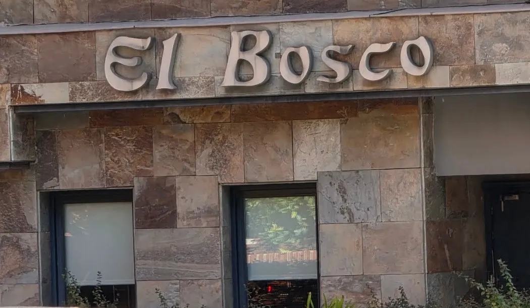 Fachada de piedra pizarra con las letras en relieve de «El Bosco» sobre dos ventanas